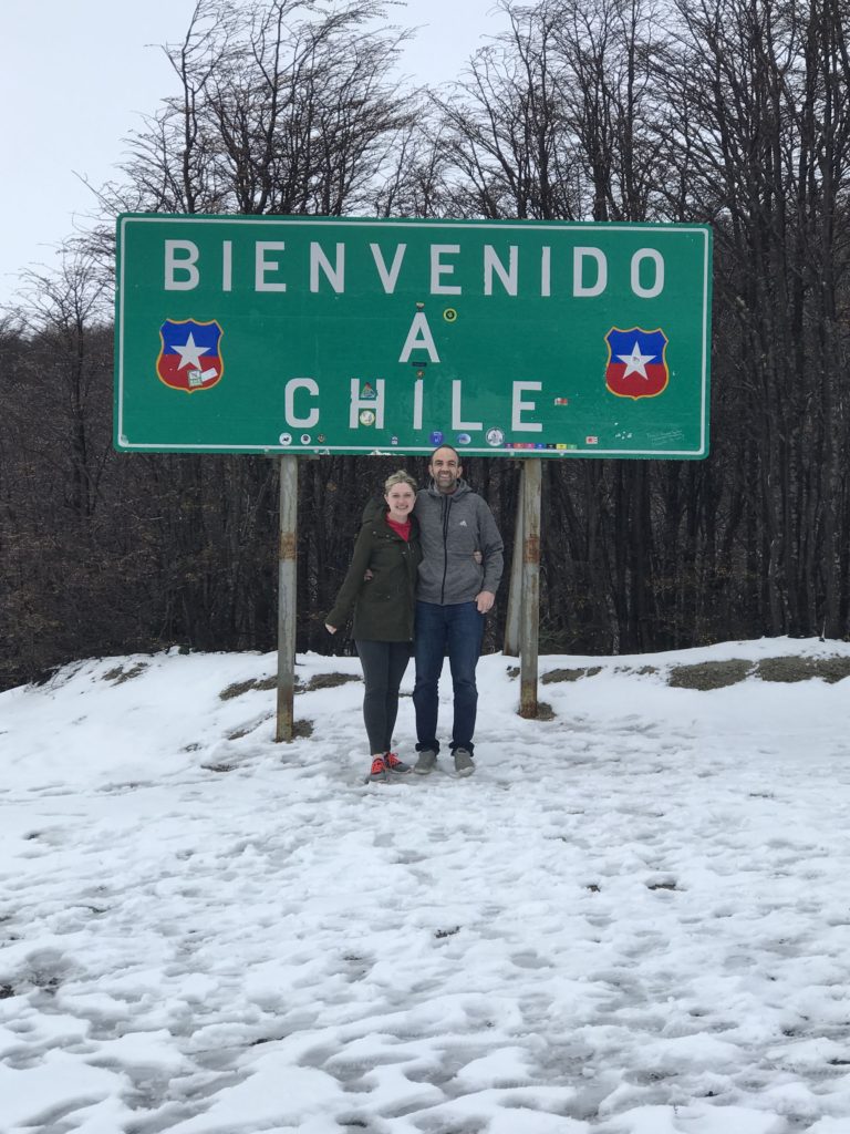 Couple in front of the Bienvenido a Chile road sign at the Argentina - Chile border.