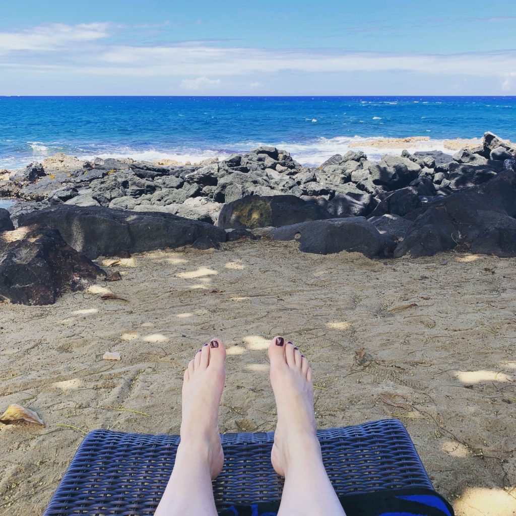 My secrets to budget travel allow me to relax on the beach in Kona, Hawaii. 