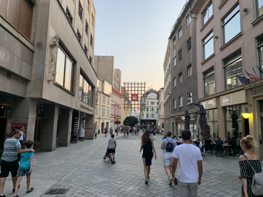 People walking on one of the main roads in the Bratislava city center with restaurants and shops.