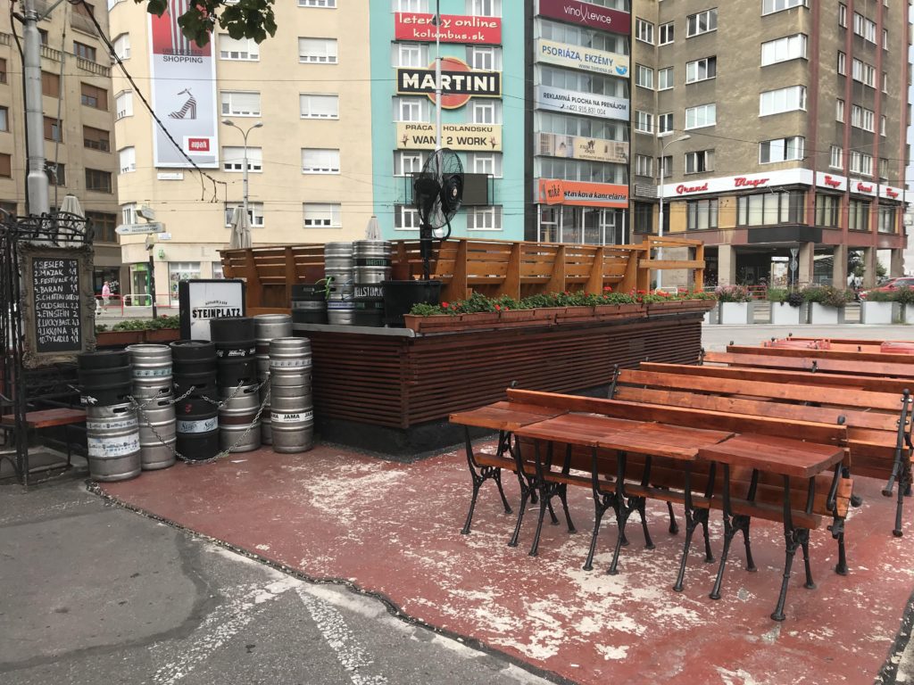 Outdoor patio with tables, chairs and kegs at Steinplatz in Bratislava