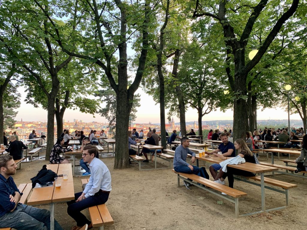 people sitting on outdoor tables at the beer garden located in Letna Park 