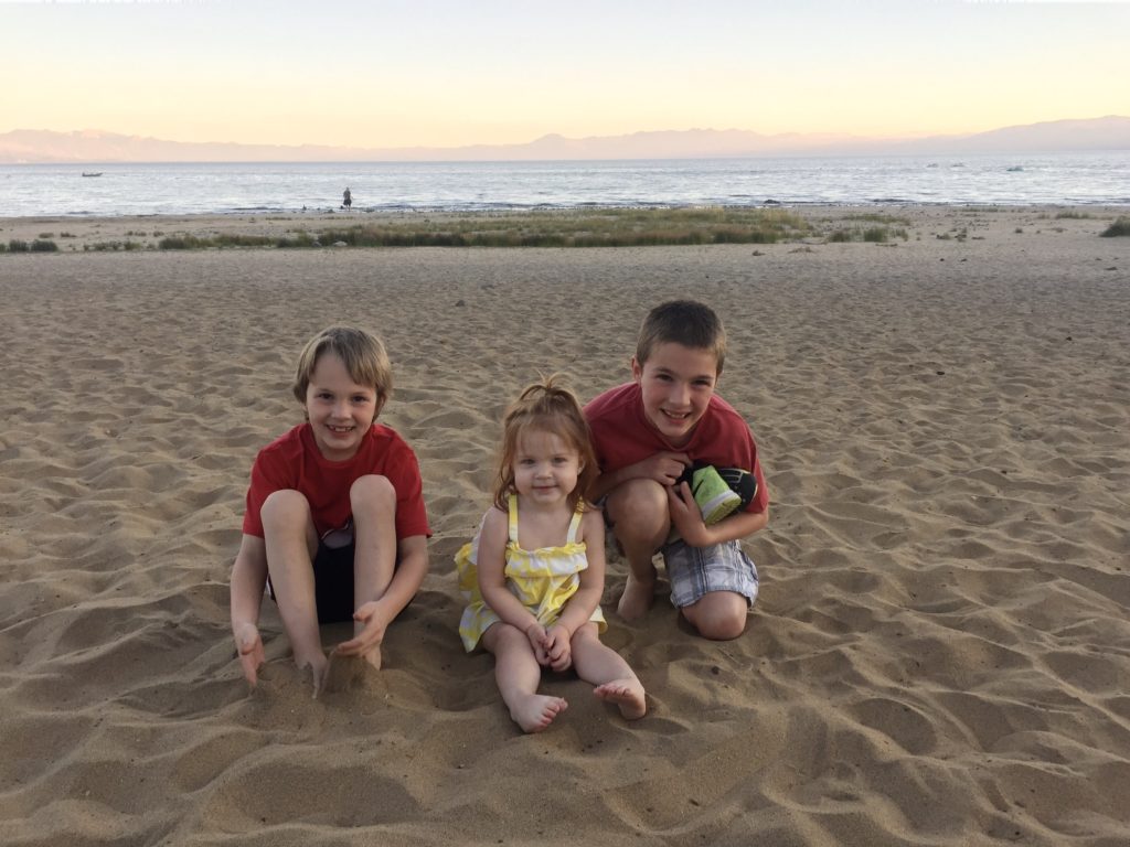 3 young kids on beach in front of lake tahoe