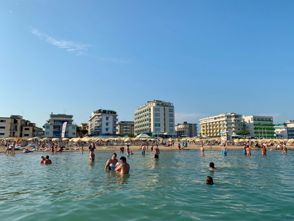 people in the water and on the beach with hotels in the background at the best beach near Venice, Italy - Lido di Jesolo