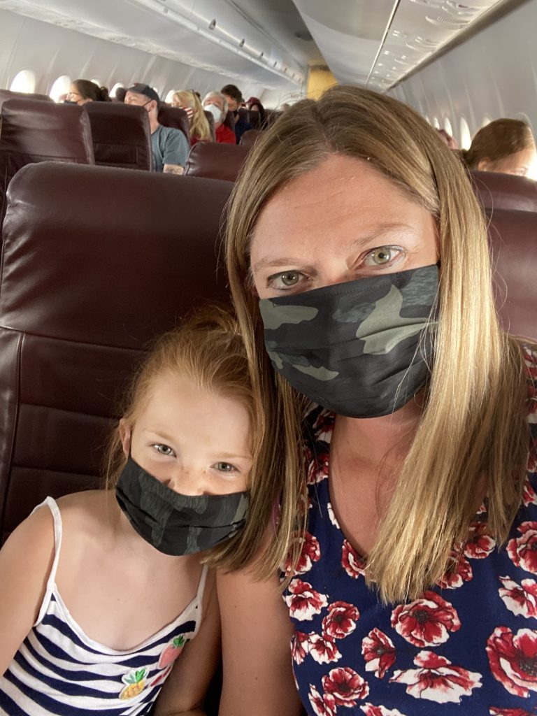 mom and daughter wearing masks on airplane while traveling during a pandemic